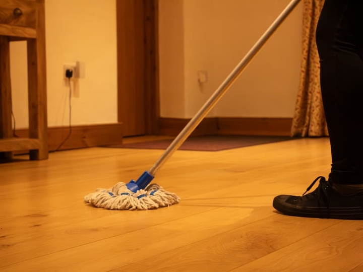 An industrious cleaning operative diligently mopping the freshly constructed floor of a new build property in Norwich, ensuring a spotless environment.