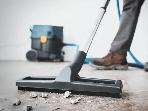 A dedicated cleaning operative use an industrial vacuum cleaner to meticulously clear debris and ensure cleanliness following a builders' clean in Norwich, creating a tidy environment.