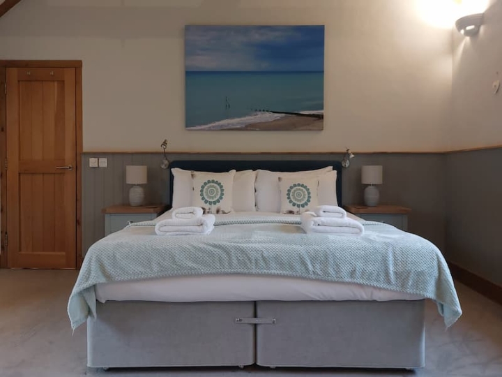 A bed in a professionally cleaned bedroom, featuring commercial laundry and freshly laundered linens, complemented by fresh fluffy towels for a welcoming and pristine atmosphere.
