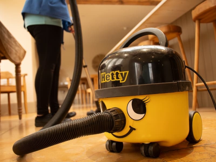 A yellow vacuum cleaner in action, providing professional domestic house cleaning services in the kitchen as part of a comprehensive full-service house cleaning.
